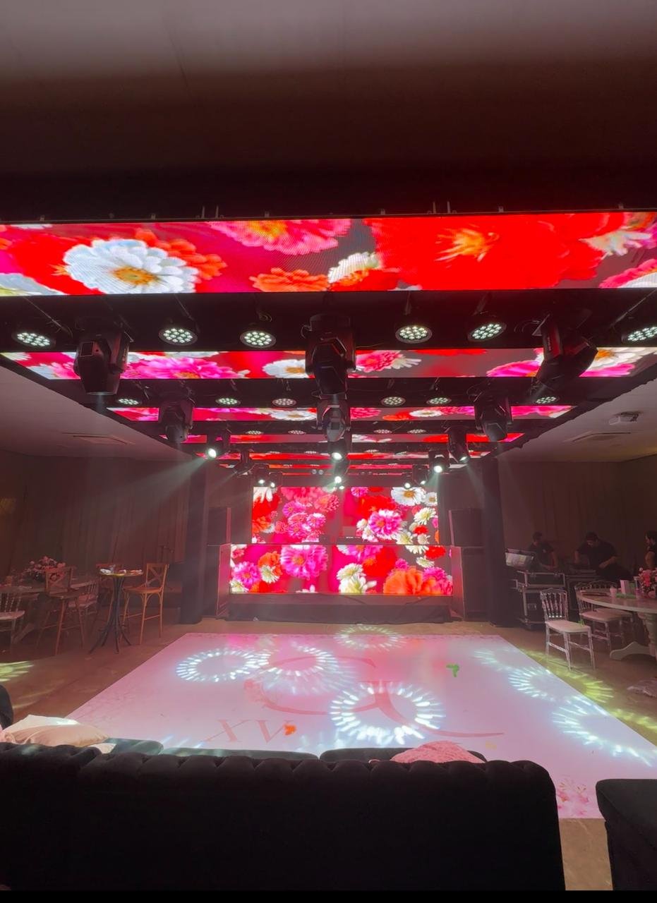 Pista de dança de luxo com painéis de LED no teto e ao fundo exibindo projeções florais vermelhas imersivas.